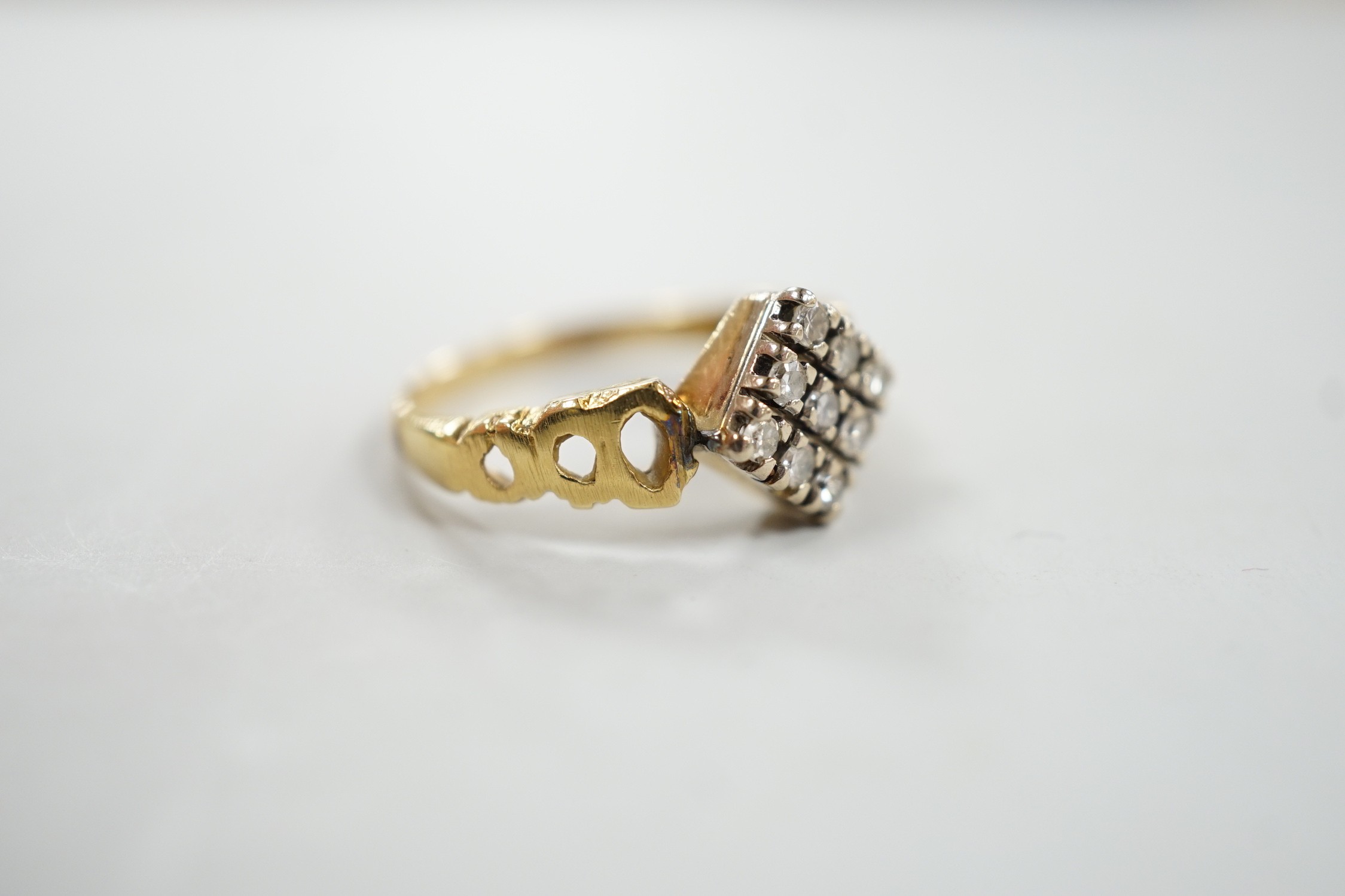 An 18ct and nine stone diamond set table ring, with pierced shoulders, size M/N, gross weight 3.7 grams.